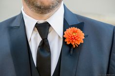 a man wearing a suit and tie with an orange flower on it's lapel