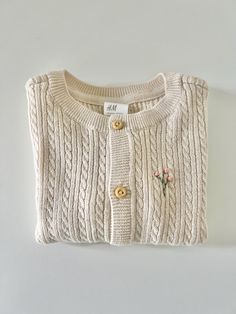 This sweet little sweater is machine knit (not handmade) but is hand embroidered by me. It is 100% organic cotton and available in size 6 months or 12 months. A beautiful creamy beige cable knit and hand embroidered with a delicate pink floral branch. Brand new.  Made in a smoke free and pet free environment. Cute Cotton Cable Knit Sweater, Cute Cream Cotton Cardigan, Beige Cotton Cable Knit Sweater, Cream Knit Sweater With Floral Embroidery, Embroidered Cream Cotton Sweater, Beige Embroidered Cotton Cardigan, Cozy Cream Cotton Sweater, Cream Cotton Embroidered Sweater, Cream Embroidered Cotton Sweater