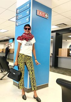 a woman standing in front of an exit sign wearing leopard print pants and a white t - shirt