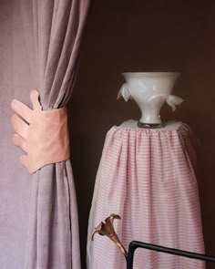 a white vase sitting on top of a window sill next to a pink curtain