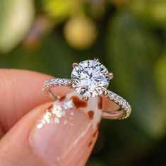 a close up of a person's hand holding a ring with a diamond on it