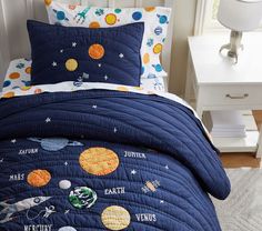 a child's bed with space themed comforter and pillow cases on top of it