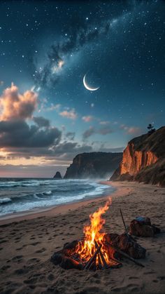 a campfire on the beach at night with stars and moon in the sky above it