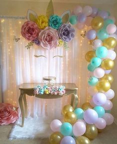 an arch made out of balloons with flowers on it and a table in the background