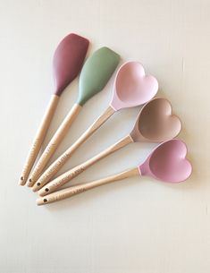 six heart shaped spoons lined up in a row on a white surface with wooden handles