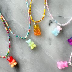 Multi Colored seed bead necklace with gummy bear acrylic charm. Sterling silver BelleStyle logo tag. Measures 16-20”. Available in Cotton Candy, Space Bears, Pink Clouds, Green Gumdrops, Sunny Bears and Rainbow Bears colors. Waterproof. Comes in linen travel pouch. Made in USA with Imported beads. Gummy Bear Beaded Necklace, Gummy Bears Necklace, Gummy Bear Necklace Beads, Gummy Bear Accessories, Gummy Bears Jewelry, Gummy Bear Bracelet, Bracelet Inspi, Gummy Bear Jewelry, Gummy Bear Charms