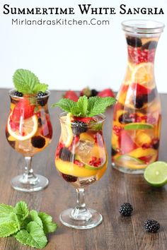 three glasses filled with different types of fruit and drinks on a table near the beach