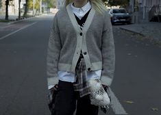 a woman standing in the middle of an empty street with her hands in her pockets