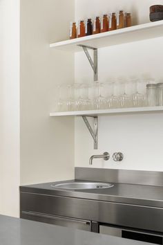 a stainless steel kitchen sink with shelves above it