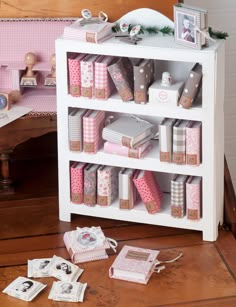 a white shelf filled with lots of pink and silver items on top of a wooden floor