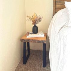 a small table with flowers on it next to a bed