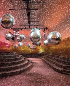 an empty stage with shiny balls hanging from the ceiling and steps leading up to it