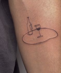 a man's arm with a wine bottle and glass tattoo on the left forearm