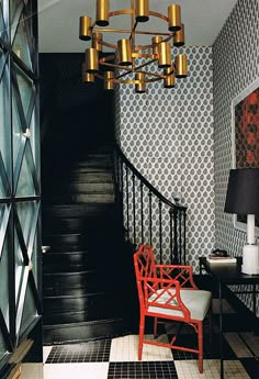 a red chair sitting on top of a wooden floor next to a black and white wall