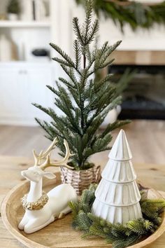 a small christmas tree sitting on top of a wooden tray next to a white deer figurine