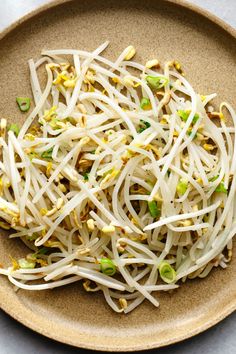 a plate filled with sprouts and sesame seeds on top of a wooden table