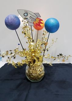 a vase filled with gold and blue decorations on top of a black cloth covered table