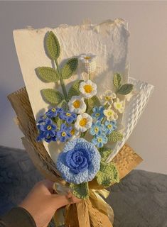 a person holding a bouquet of flowers made out of crocheted paper and yarn