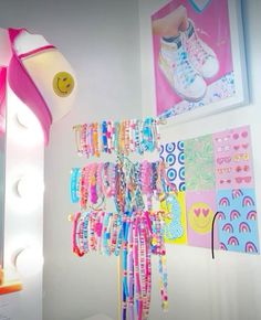 there are many bracelets hanging on the wall next to a mirror with lights around it