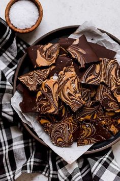 chocolate and peanut butter swirled cookies in a bowl on a plaid table cloth next to a spoon