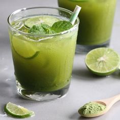 two glasses filled with green liquid and lime slices