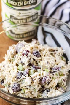 a glass bowl filled with chicken salad next to a jar of dressing