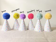 five party hats with pom - poms on them