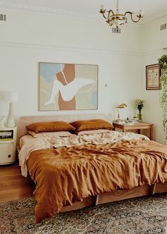 a bedroom with a bed, dresser and painting on the wall above it's headboard