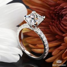 a diamond engagement ring sitting on top of a flower