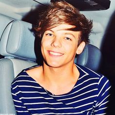 a young man sitting in the back seat of a car with his hair sticking out