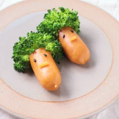 two broccoli heads with faces drawn on them are sitting on a white plate