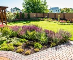 a garden with lots of green grass and purple flowers in the center, surrounded by brick walkways