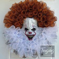 a creepy clown mask hanging on a door with orange hair and white makeup, as if it were from the movie it's dark knight