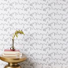 a table with a vase on top of it next to a wallpapered wall