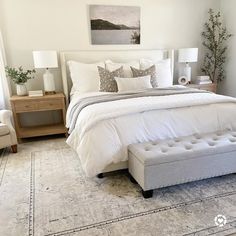 a bedroom with a large bed and white furniture