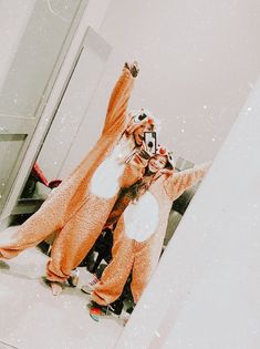 two people dressed up in animal costumes standing next to each other on the floor with their arms raised