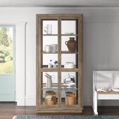 a wooden cabinet with glass doors in a living room next to a white couch and blue rug