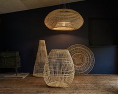 three wicker vases sitting on top of a wooden table next to a lamp