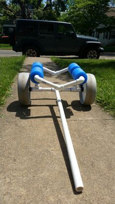 a white and blue tricycle with two wheels on the sidewalk in front of a black truck