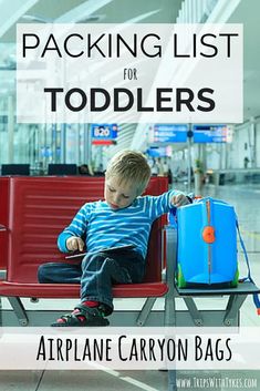 a young boy sitting on top of a red chair next to an airport luggage bag