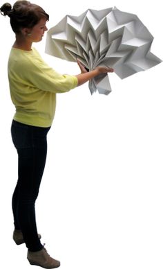 a woman is holding an origami flower