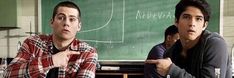 two men sitting at a table in front of a blackboard