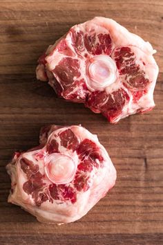 two pieces of raw meat sitting on top of a wooden table next to each other