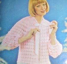 a woman wearing a pink sweater and white pants with a tie around her waist,