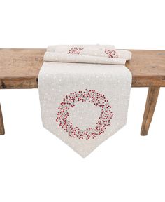 a white table runner with red dots on it and a wooden bench in the background