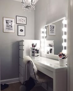 a white vanity with lights on it and a chair in front of the mirror that is lit up