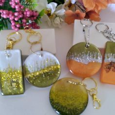 four different types of key chains and pendants on a white table with flowers in the background