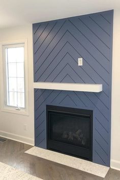 an empty living room with a fireplace and blue painted accent wall in the corner, along with hardwood flooring