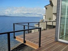 a balcony overlooking the ocean with glass doors and railings on both sides, looking out to the water