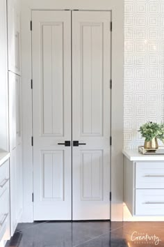 two white doors in a kitchen next to a counter top and cabinets with vases on it